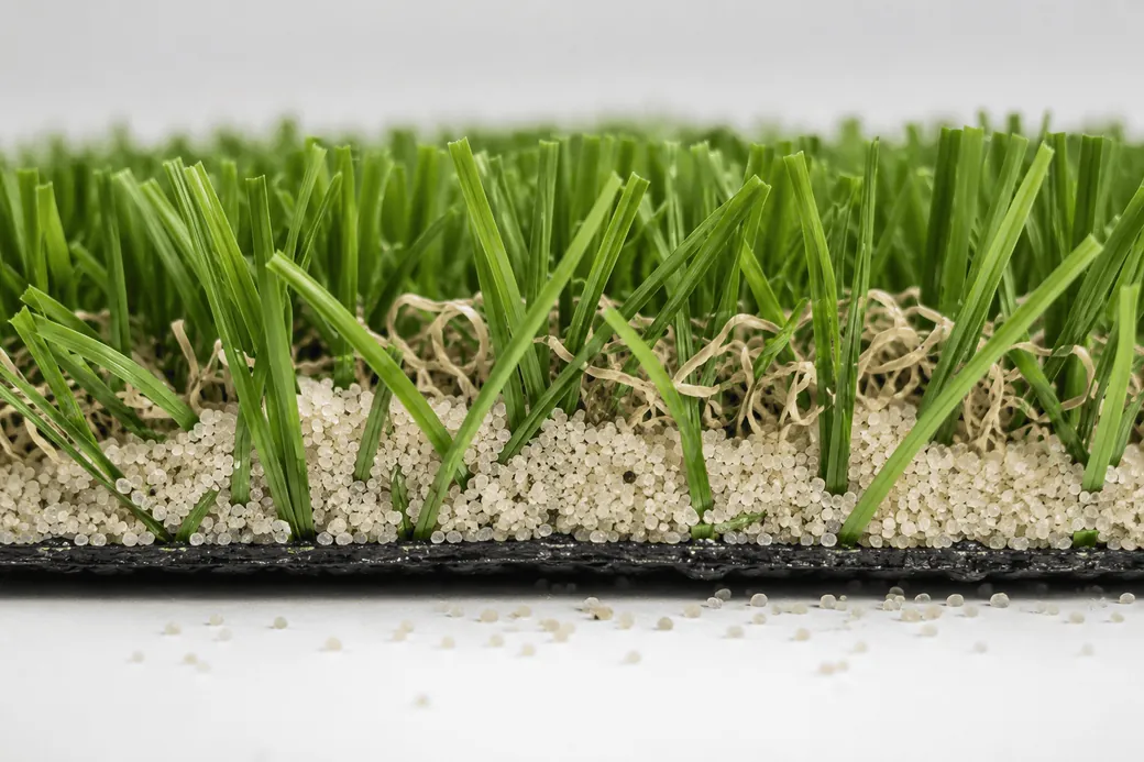 Cross-section of sports turf showing rounded silica sand ballast at the base of the pile